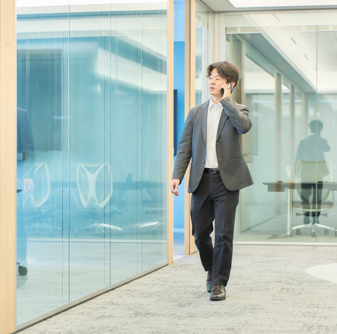 電話をしながらオフィスを移動する佐藤さん
